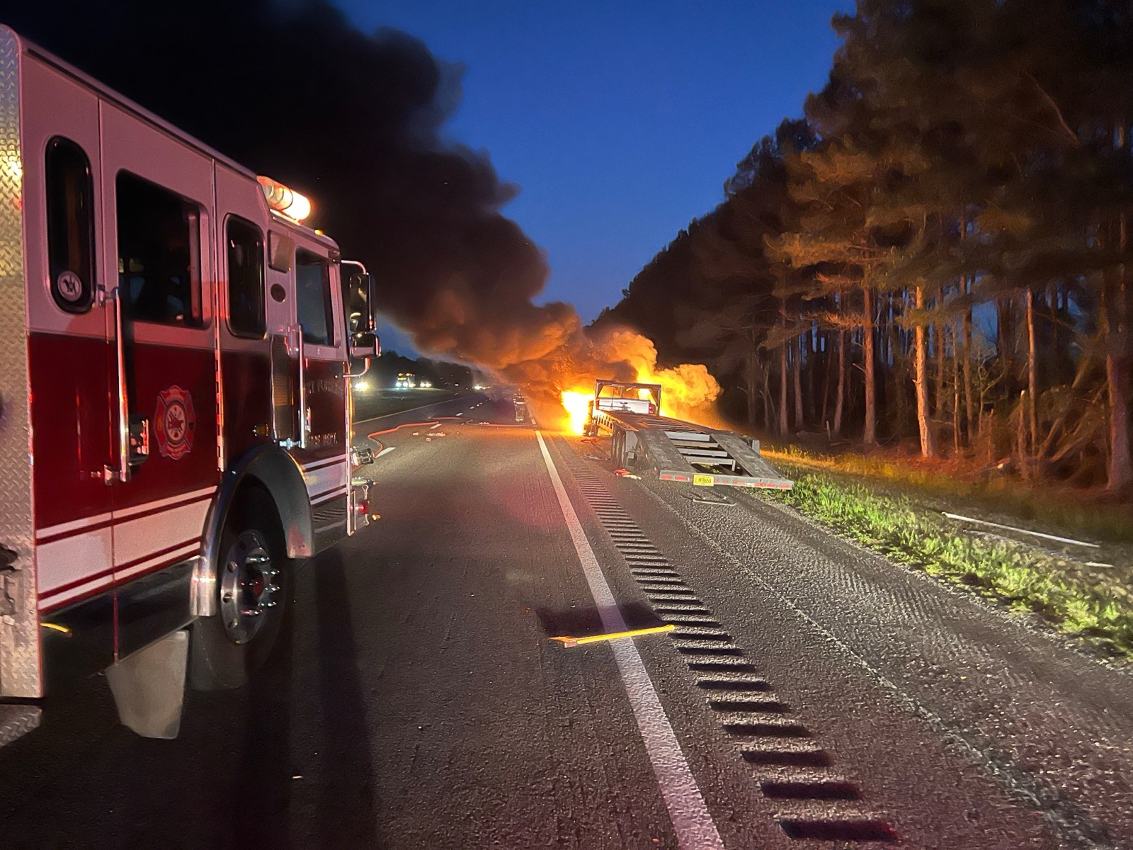 Engine on the interstate at dusk with a vehicle fully involved in fire