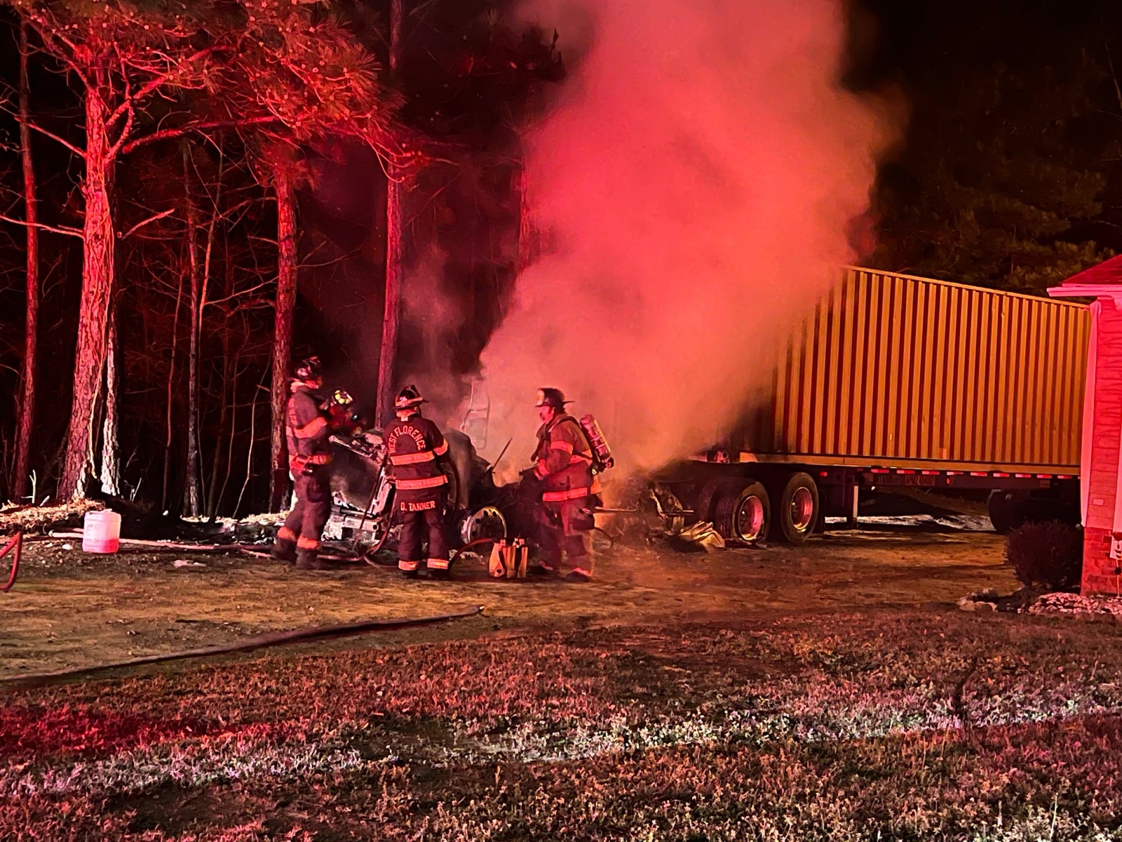 Firefighters working a nighttime scene near a tractor-trailer