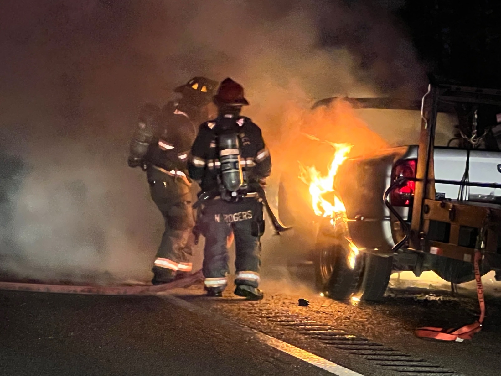 Two firefighters working a pickup truck fire at night