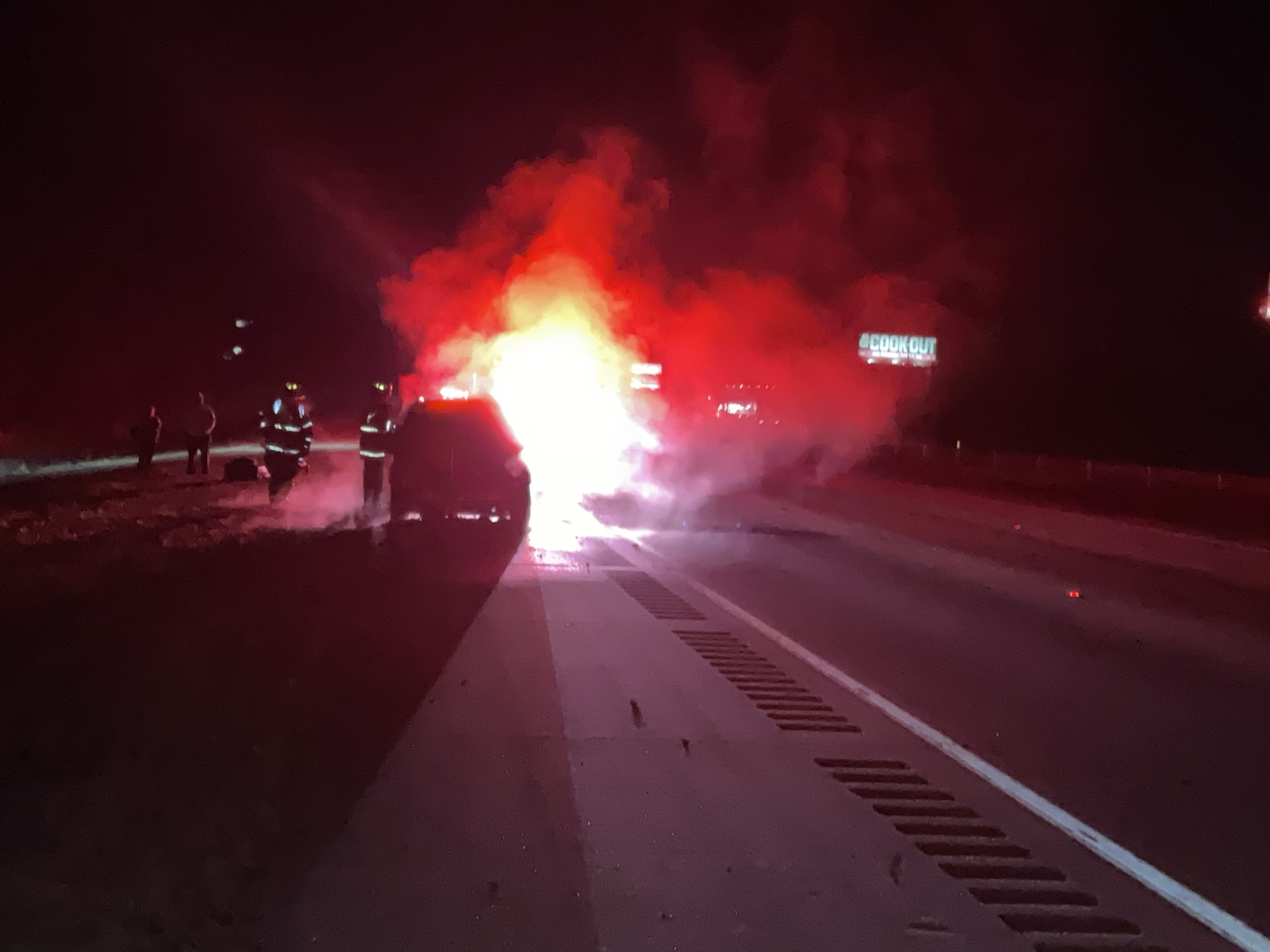 Vehicle fire fully involved on a highway at night