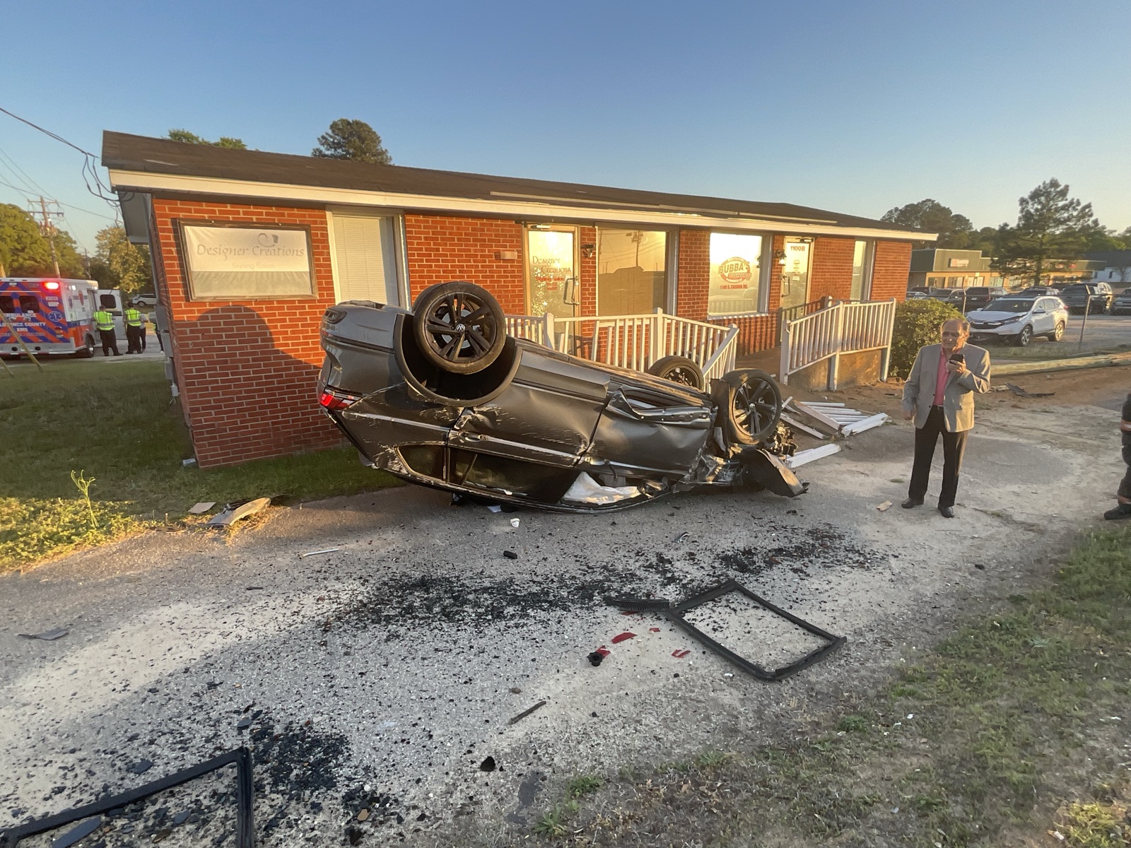 Single-vehicle rollover on its roof in front of a building at dusk