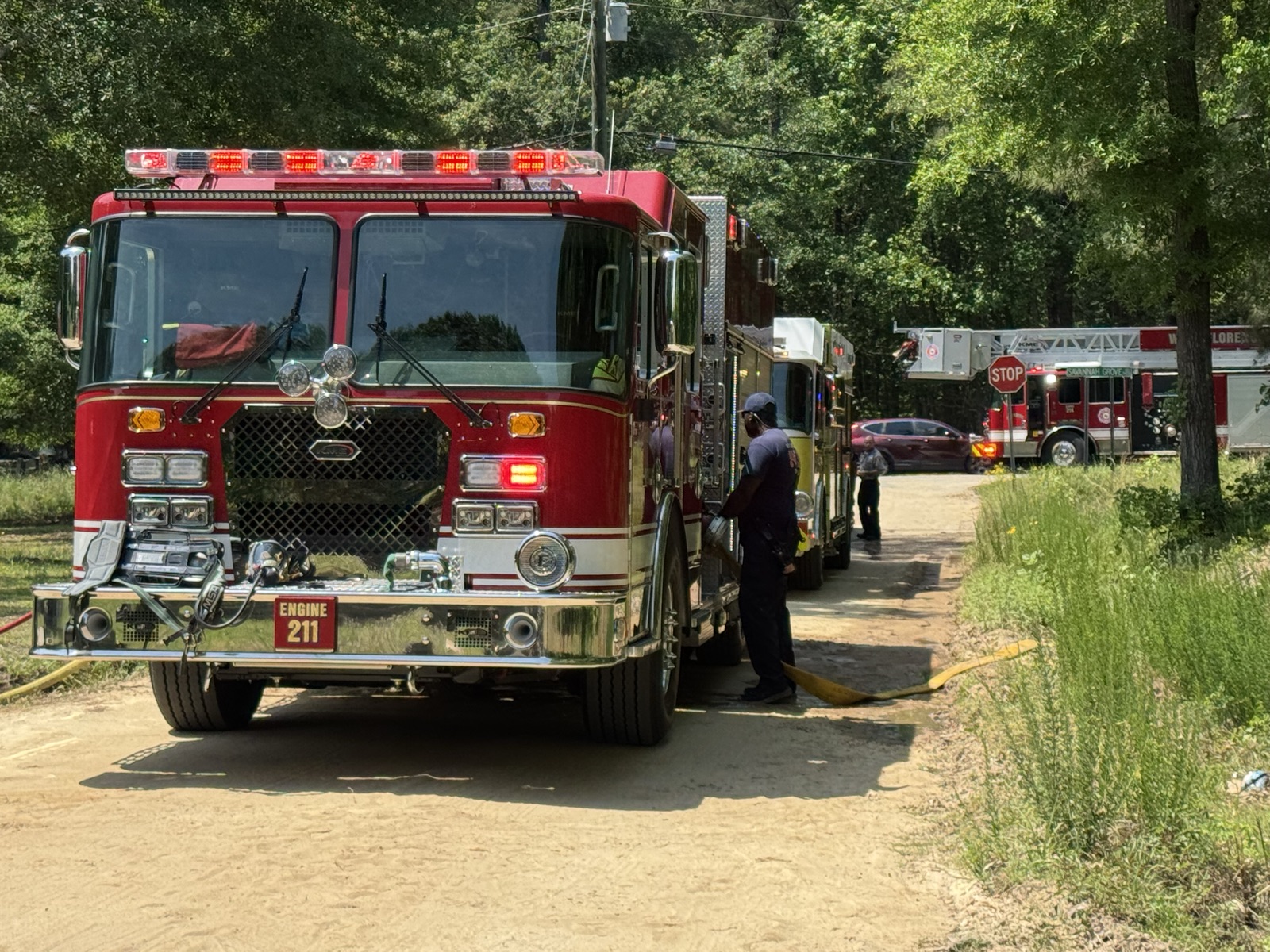 Engine 211 staged on a dirt road in summer with crew working